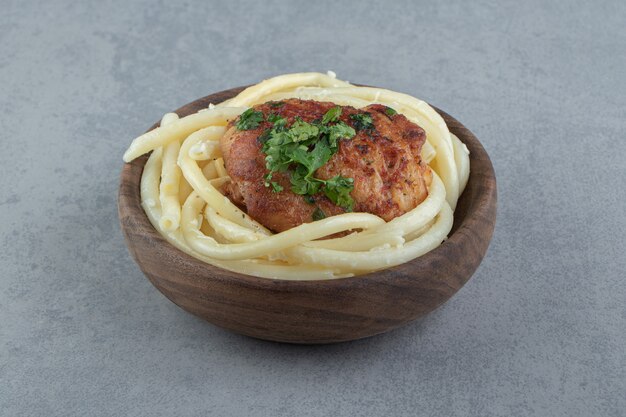 Вареные макароны спагетти и жареный цыпленок в деревянной миске.