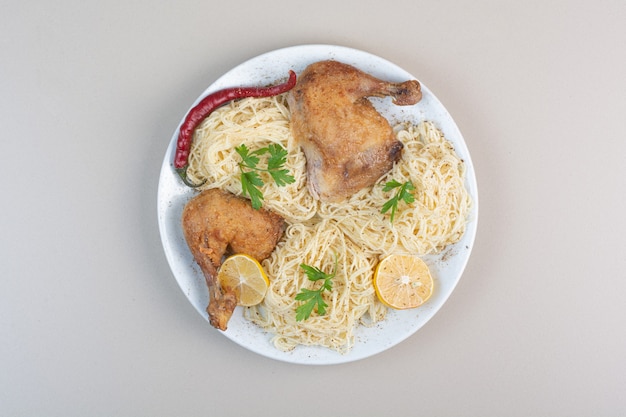 Foto gratuita spaghetti bolliti, pepe e cosce di pollo sul piatto bianco