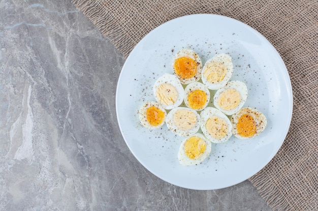 Вареные вкусные яйца со специями на белой тарелке. Фото высокого качества