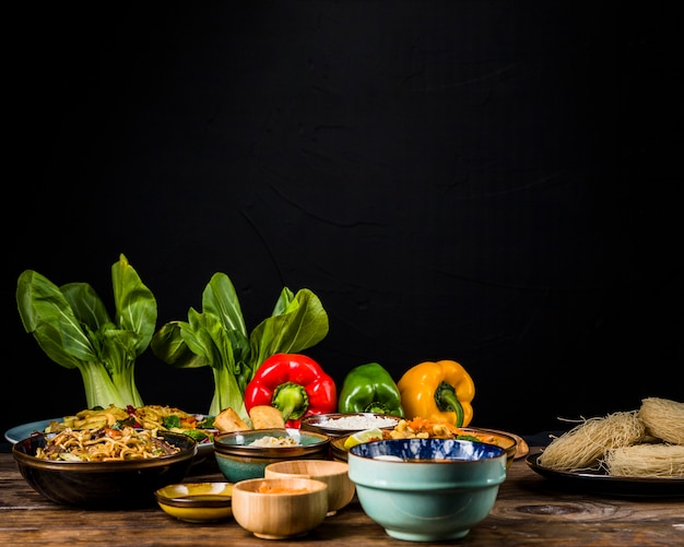 Foto gratuita bokchoy; peperoni dolci e cibo tradizionale tailandese sul tavolo contro sfondo nero