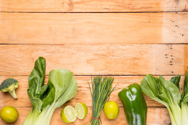 Bokchoy; broccoli; lemon; bell pepper; chives on wooden desk