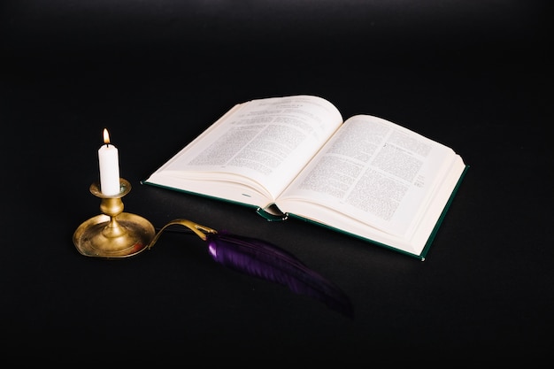 Book and candlestick on black