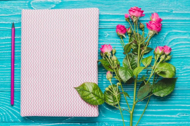 Book and decorative flowers on blue wooden surface