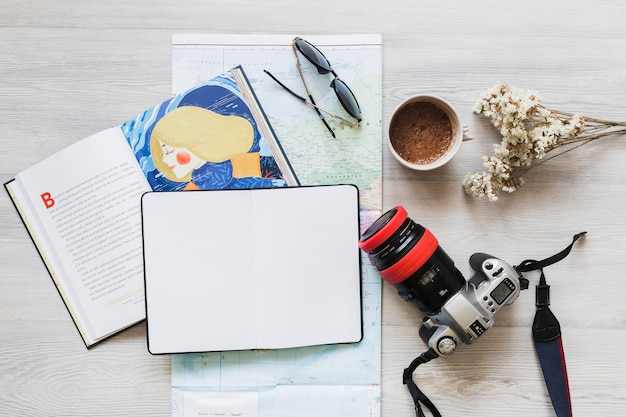 Book and diary over the map with personal accessories on desk