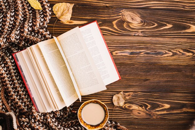 Book and drink near scarf and leaves