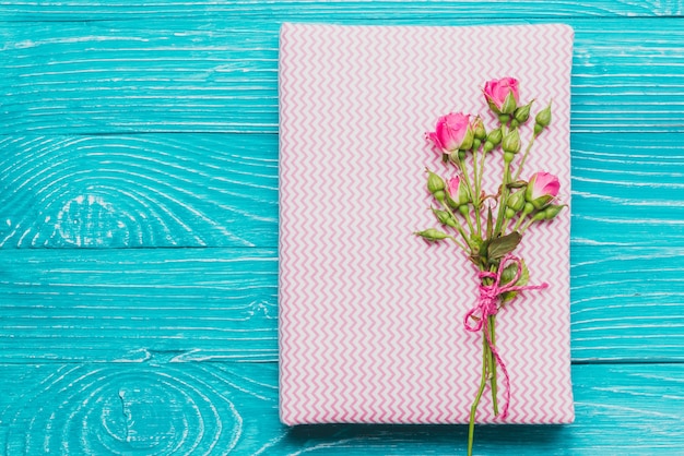 Foto gratuita libro e fiori sulla superficie di legno