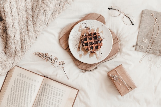 Book, food and other things on bedsheet