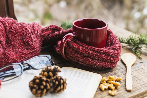 Book and glasses near sweater and hot drink