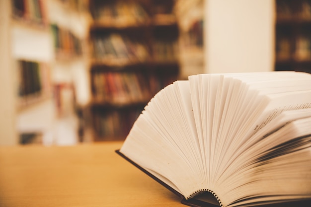 Book in library with old open textbook, stack piles of literature text archive on reading desk