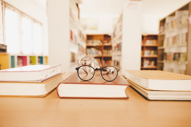 Book in library with old open textbook, stack piles of literature text archive on reading desk