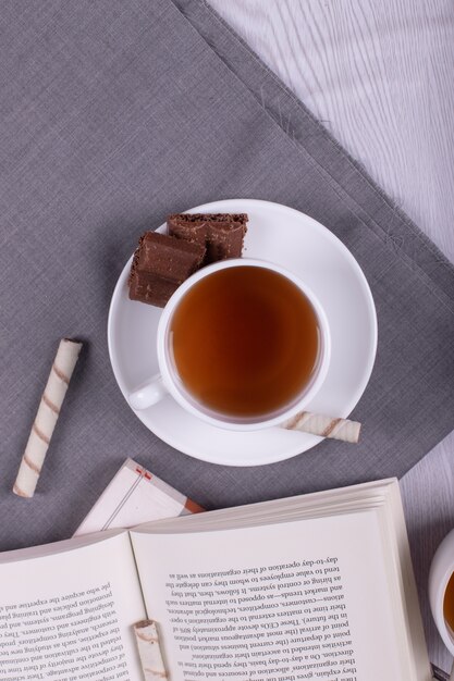 Book, Sweet snacks and cup of tea on the table