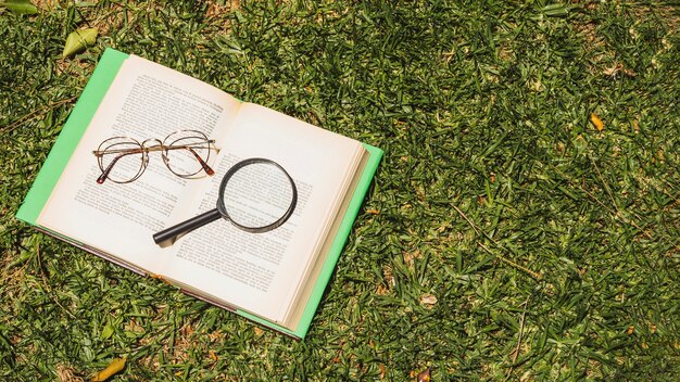 Book with optical implements on green grass