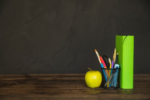 Book with pencil cup and apple on desk