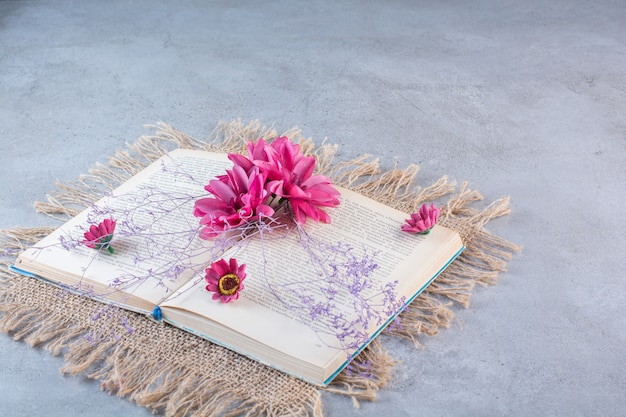 Free photo a book with purple flowers on sackcloth