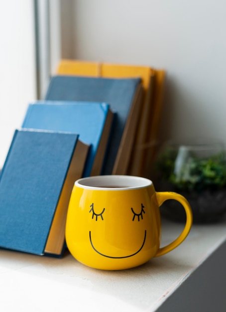 Бесплатное фото Расположение книг и желтая чашка