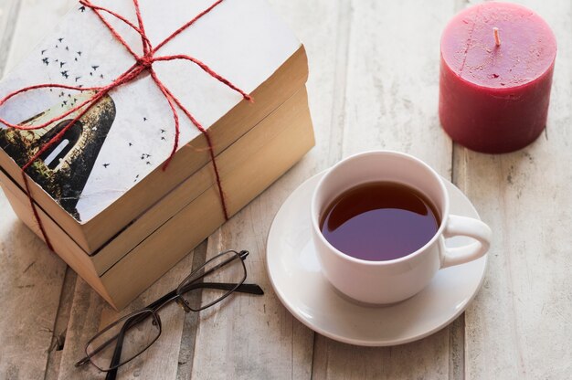 Books, coffee, candle and glasses on wooden table