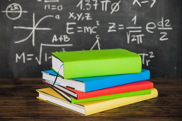 Books on desktop near chalkboard