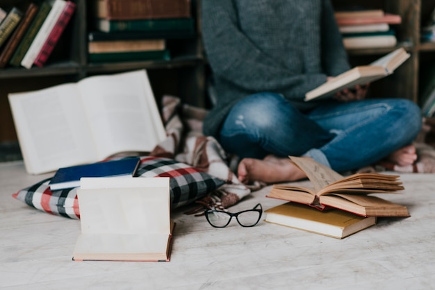 Books and glasses near reading woman