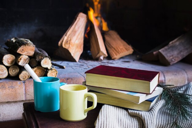 Books and mugs near fireplace
