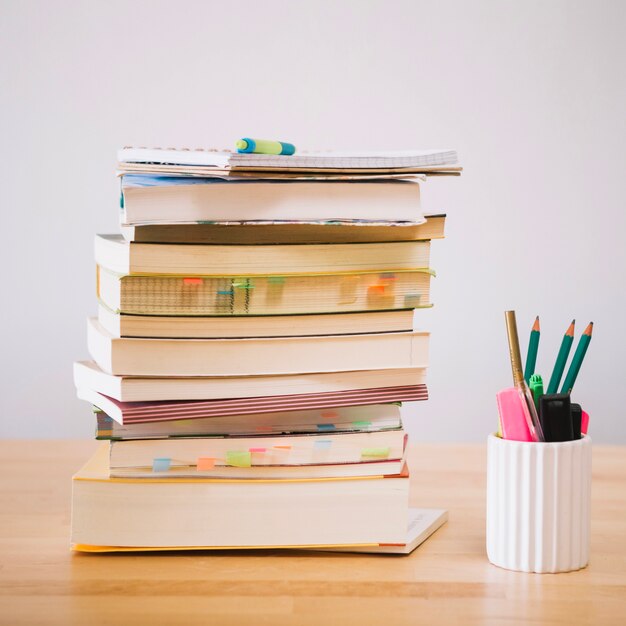 Books and notebooks near cup with pencils