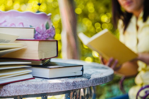 Books on table and woman reading