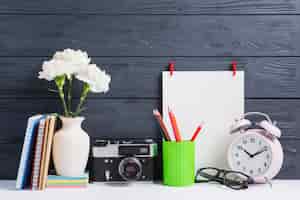 Free photo books; vase; vintage camera; eyeglasses; pencil holders and white blank paper on wooden backdrop
