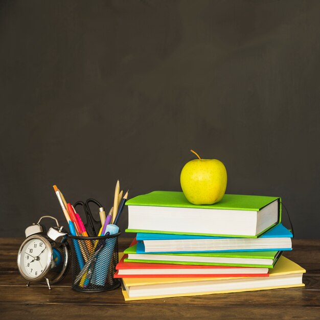 Books with stationery and clocks on table