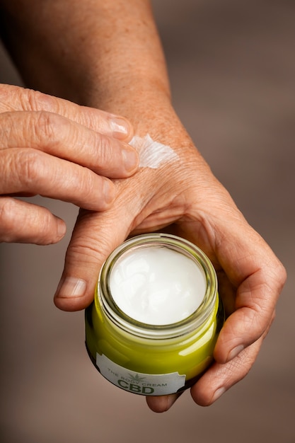 Foto gratuita boomers che usano olio e crema di cbd per trattare il dolore corporeo