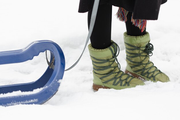 Boots in snow and blue sleigh