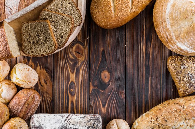 Border of different baked breads on the wooden backdrop