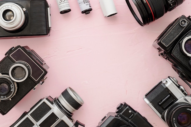 Border from cameras and film on pink background