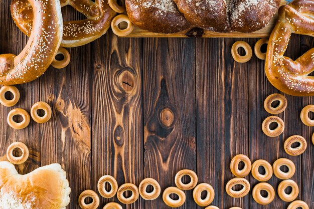 Граница, сделанная из свежеиспеченного плетеного хлеба, кренделя и бубликов на деревянном фоне