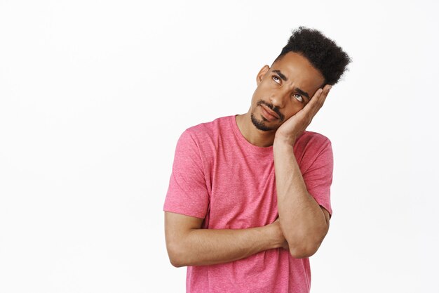 Bored and annoyed african american male student, guy roll his eyes and staring with empty spaced out face at upper left corner, attend annoying boring meeting on white