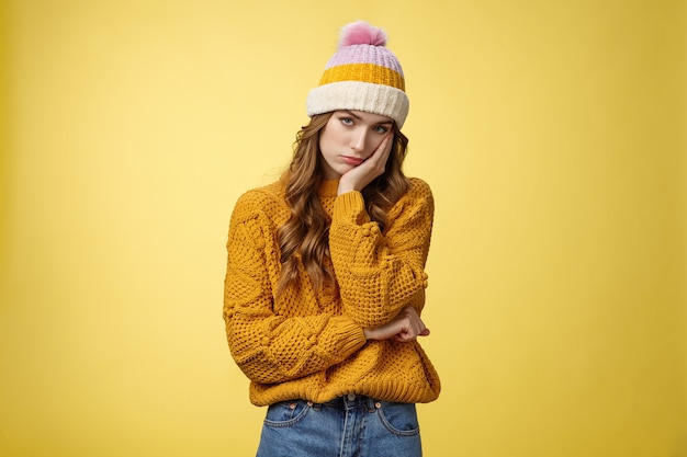 Bored annoyed fed up cute girlfriend cannot stand boring talks leaning palm indifferent look camera under forehead uninterested not paying attention, standing bothered yellow background