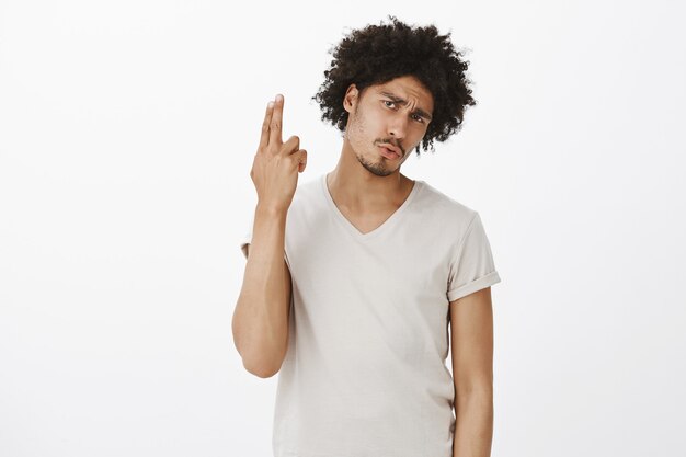 Bored attractive man blowing his brains, making hand gun gesture from annoyance