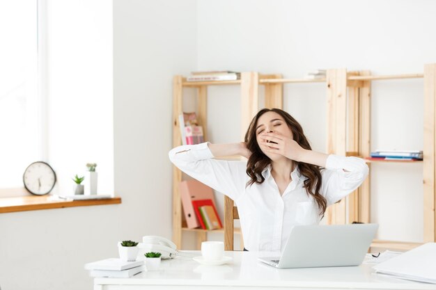 Bored business people woman sitting at desk with closed eyes and yawning Young caucasian business woman at her office