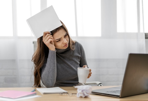 Foto gratuita donna di affari annoiata che tiene un blocco note in bianco