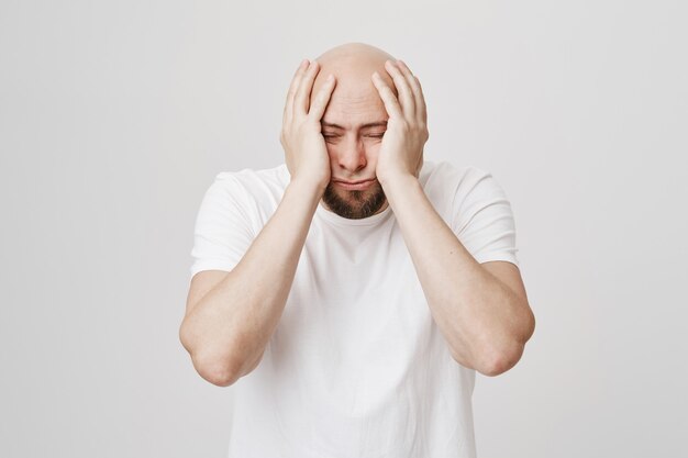 Bored and gloomy bald guy grab head depressed