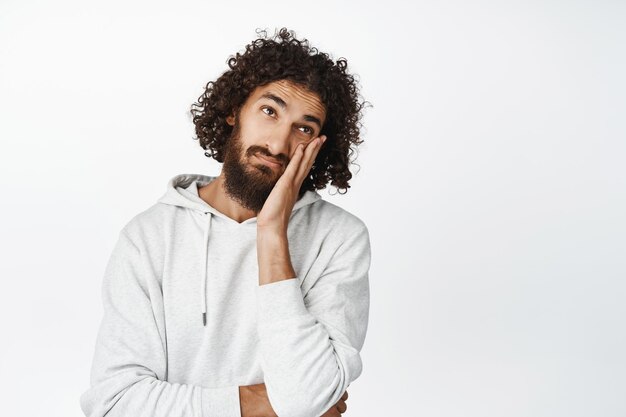 Bored hispanic man roll eyes lay head on hand annoyed unamused and uninterested standing over white background