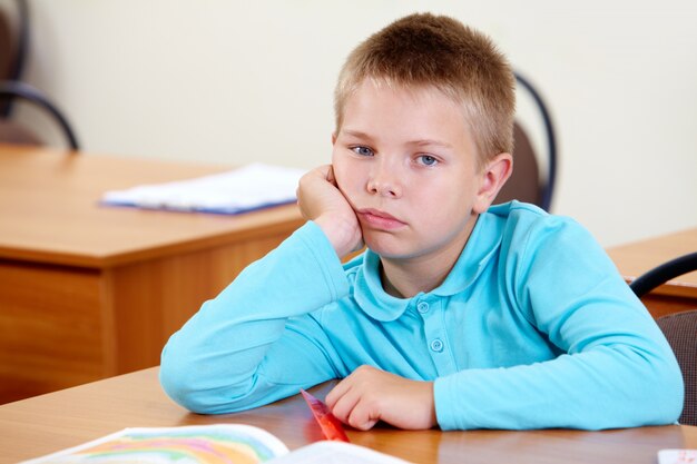 Bored little boy at his desk