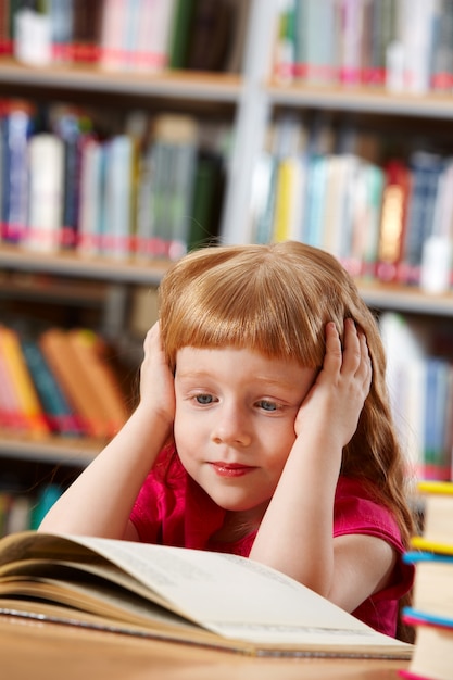 Бесплатное фото Скучно маленькая девочка в библиотеке