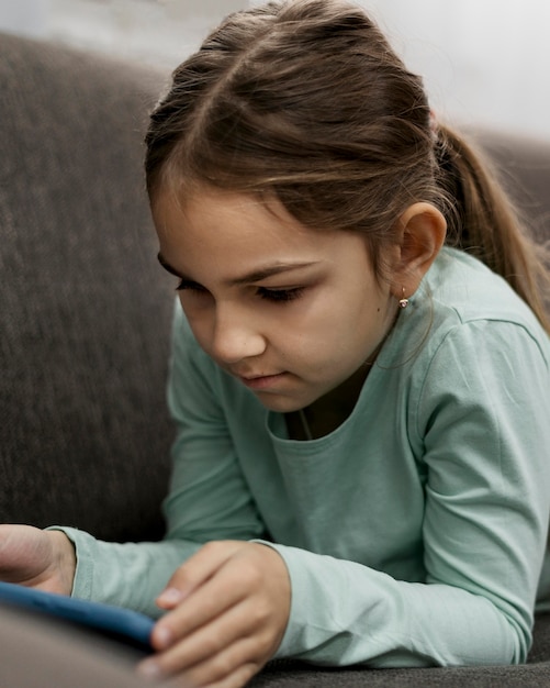 Free photo bored little girl playing on a smartphone at home