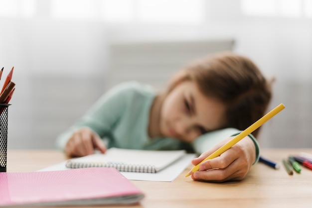 Скучно маленькая девочка отдыхает головой, делая домашнее задание