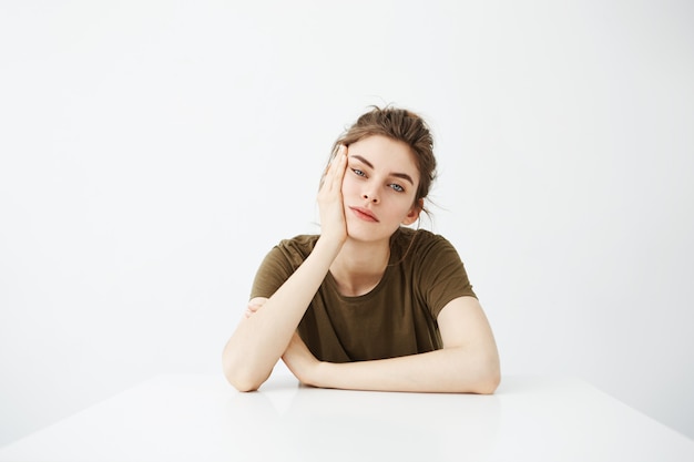 Bored tired young woman student with bun sitting at table