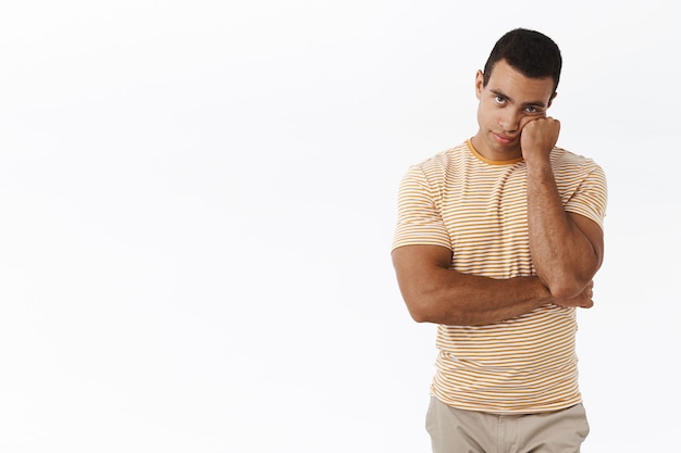 Bored and unamused caucasian man standing white background reluctant