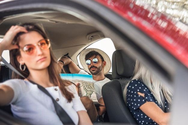 Bored woman travelling by car in front of man looking at map for direction
