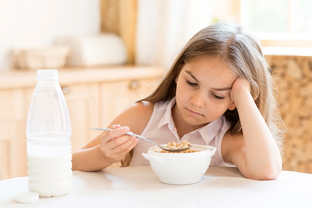 Bored young girl eating cereals for breakfast