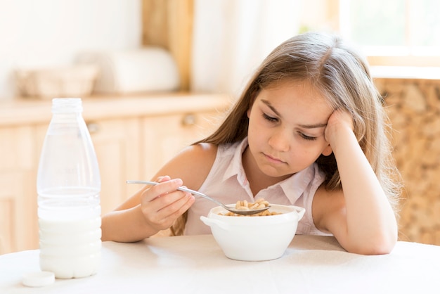 Bored young girl eating cereals for breakfast