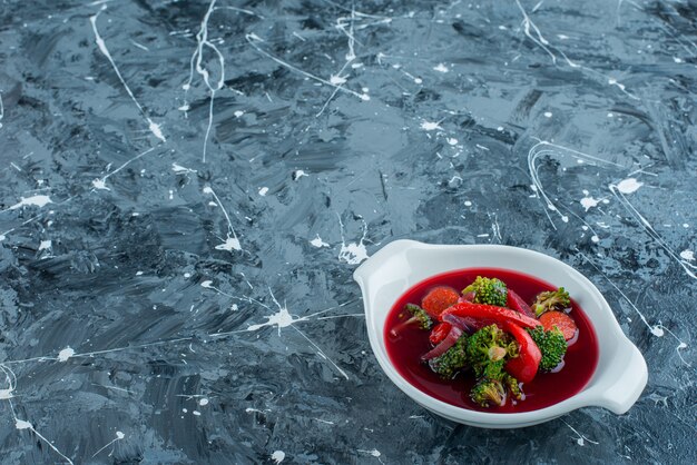 Borsch soup in a bowl, on the blue background. 