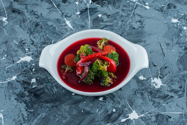 Borsch soup in a bowl, on the blue background. 
